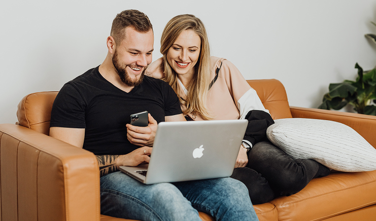 Un couple détendu consulte un ordinateur sur un canapé